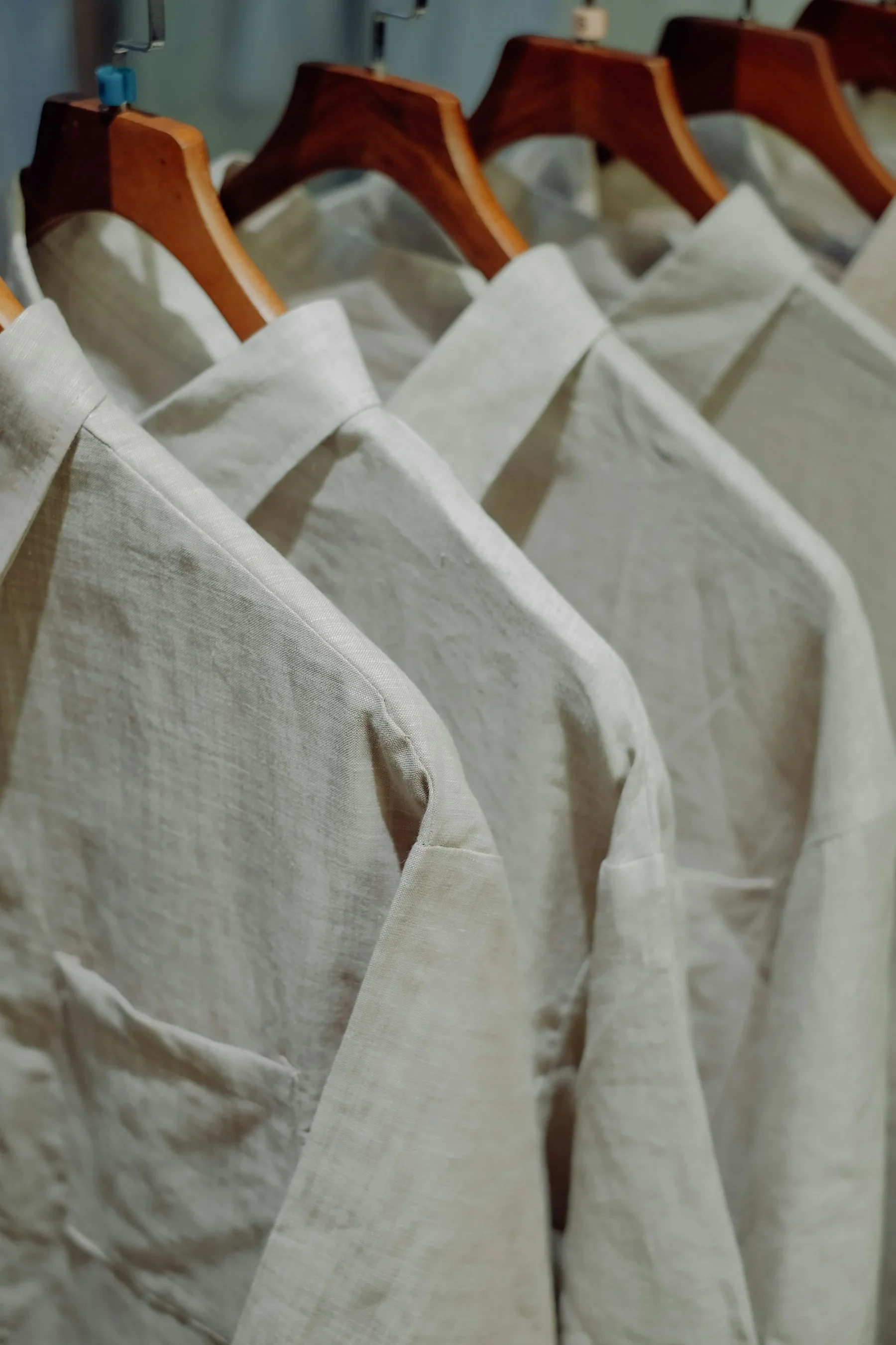 Neutral linen shirts on wooden hangers